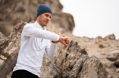 Young Man in Nature Looking at Watch Near Rocks