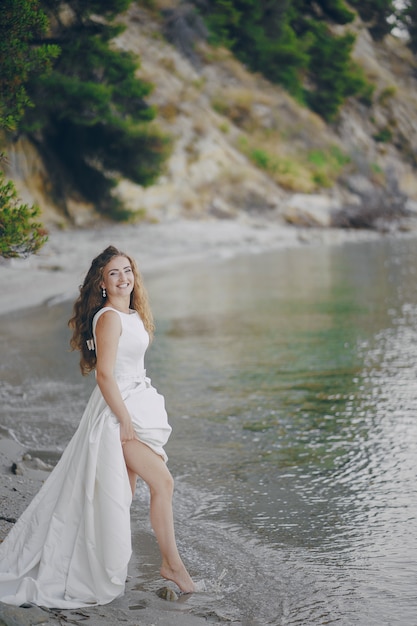 Beautiful Long-Haired Bride in a Magnificent White Dress Walking on a Beach