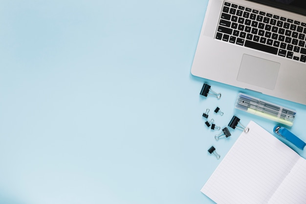 Elevated view of laptop and stationeries on blue backdrop