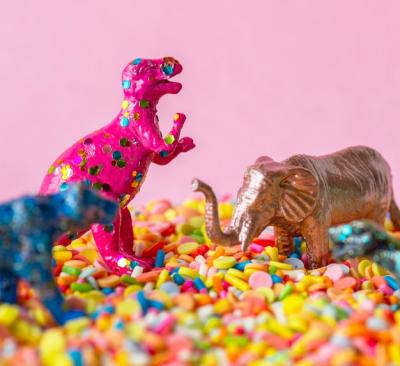 Close up of dinosaurs and animal figure toys on sweet candy sprinkles