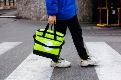 Man Carries Order in Light Green Bag on Pedestrian Zebra Road