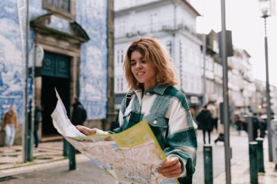 Young woman wearing denim shirt walking on the street city with a map