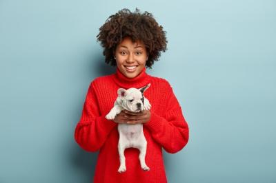 African American woman holding dog in red sweater