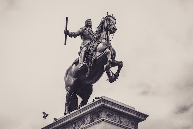 Low Angle Grayscale Shot of Statue in Front of Royal Palace of Madrid