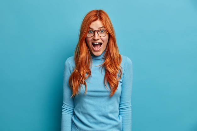 Young Redhead Woman Reacting in Shocked Expression with Mouth Opened