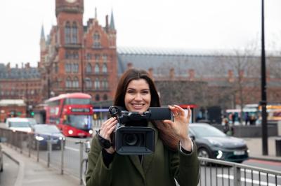 Smiley reporter holding camera medium shot