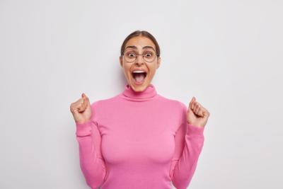 Victorious Young Woman Celebrating in Pink Turtleneck