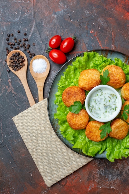 Top View Cheese Balls on Plate with Sauce Cherry Tomatoes Wooden Spoons Black Peppers on Dark Surface