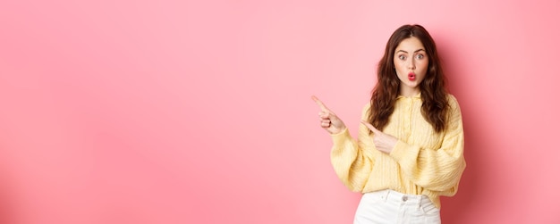 Surprised Brunette Woman Showing Promotional Text Gasping Amused Pointing Fingers Aside to Left