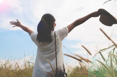 Woman Traveler with Camera in Field of Yard and Forest