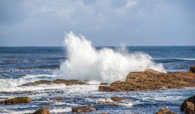 Rocks surrounded by the wavy sea under the sunlight and a cloudy sky at daytime in South Africa