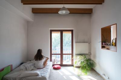 Young woman sitting on bed and looking through the window