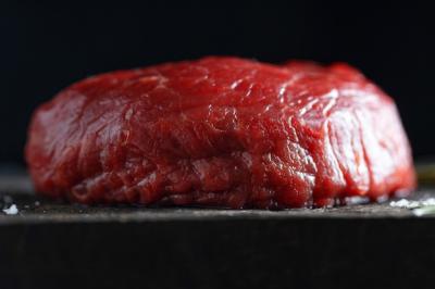 Peace of meat with salt and rosemary on dark board Closeup