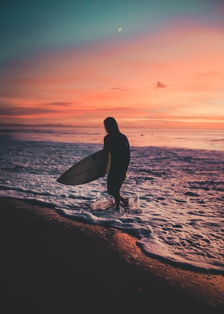 Surfer Walking Out of the Sea During Sunset