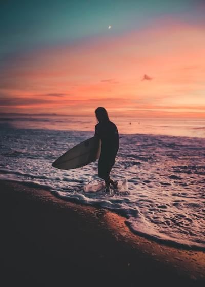 Surfer Walking Out of the Sea During Sunset