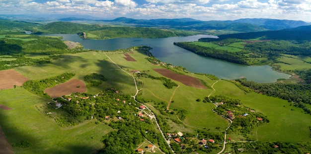 Aerial Shot of Green Landscapes, Fields, and a River on a Sunny Day under Cloudy Sky