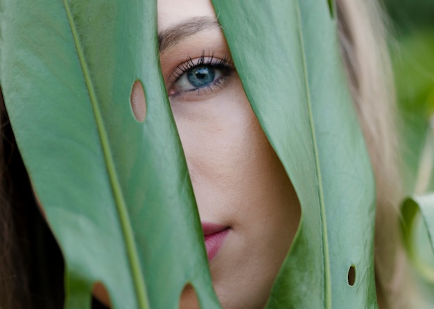 Close-up female watching through leaves – Free Download