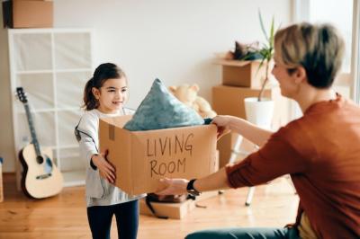 Happy Little Girl and Her Mother Unpacking Their Belongings While Moving Into New Home