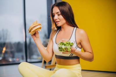 Woman Eating Salad Isolated on Yellow Background