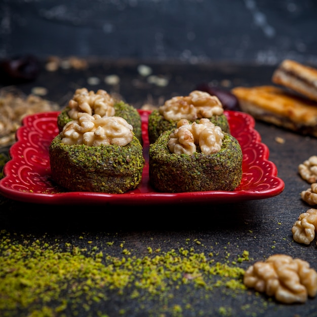 Side view pistachio cookies in red plate on black background