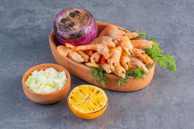 Clay Plate of Delicious Shrimps with Lemon and Onion on Stone Surface