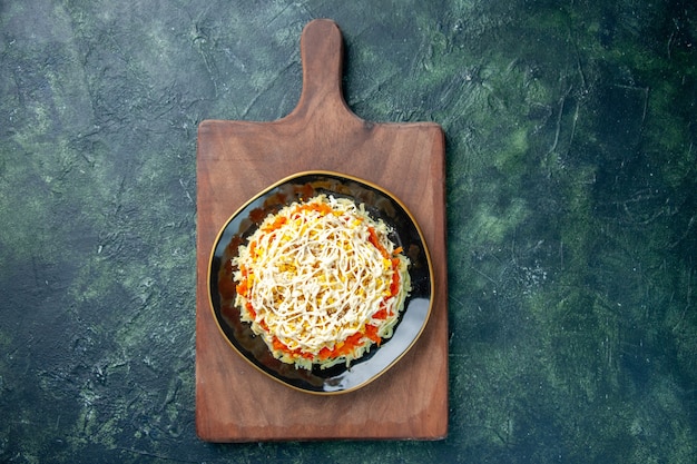 Top view of tasty mimosa salad inside plate on dark-blue surface