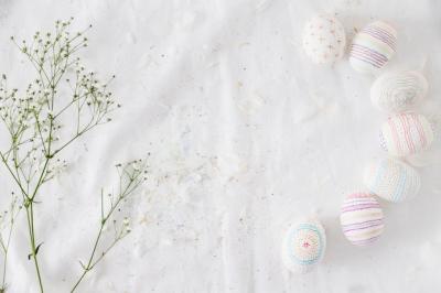 Row of Easter eggs with patterns near plant twig and feathers on textile – Free Stock Photo