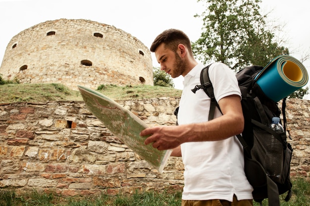 Side view man at castle ruins with map