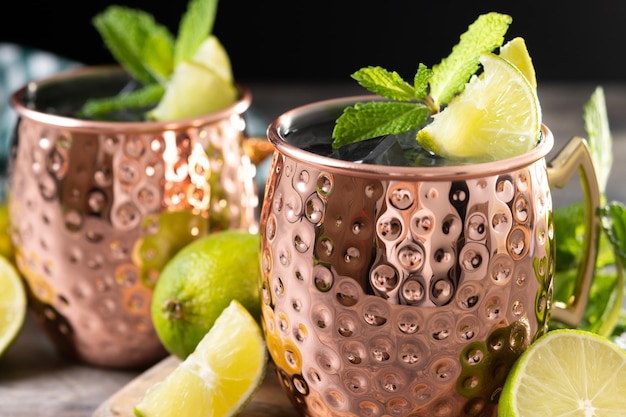 XAMoscow mule cocktail served with ice and lime slice on wooden table