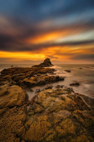 Vertical Shot of Stones at the Seaside During Sunrise