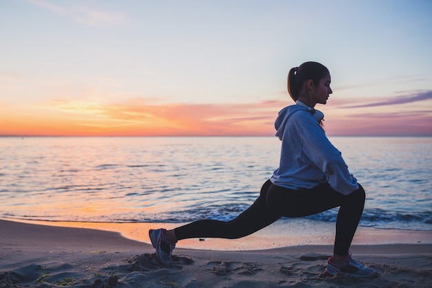 Youthful Woman Engaging in Fitness Routines on Sunrise Beach in the Morning