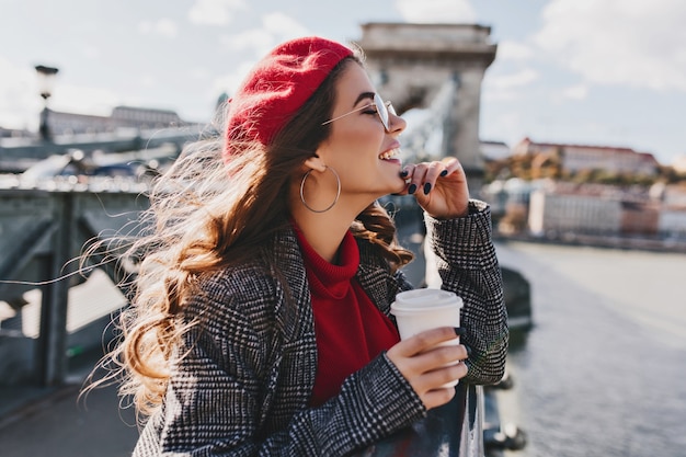 Carefree Caucasian Woman in Red Hat Enjoying City Views in Warm Windy Day