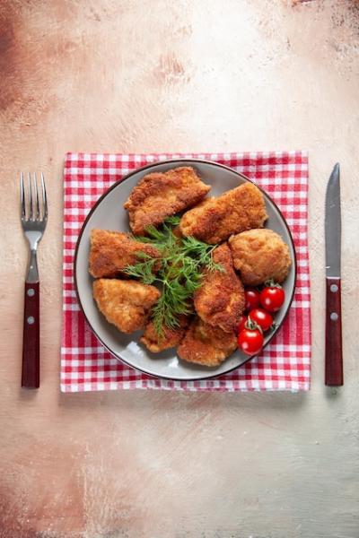 Top view tasty chicken wings with greens and tomatoes on light background