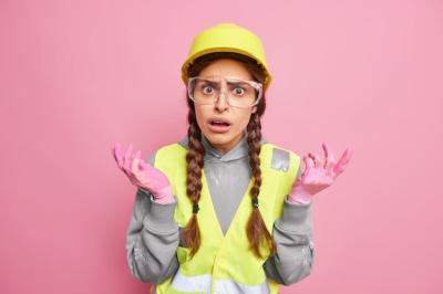 Indignant Displeased Woman Builder Industrial Worker Shrugs Shoulders Feels Puzzled Spreads Hands Sideways Wears Protective Hardhat Glasses Reflective Vest Works at Factory or Construction Site