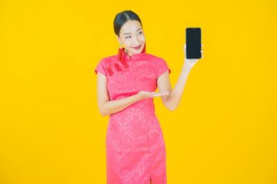 Portrait of Beautiful Young Asian Woman Smiling with Smartphone on Color Background