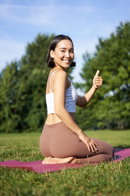 Asian Woman Practicing Yoga in Park with Thumbs Up