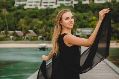 Attractive Woman in Black Dress Posing on Pier at Luxury Resort Hotel