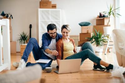 Happy couple using laptop while relaxing on the floor at their new home