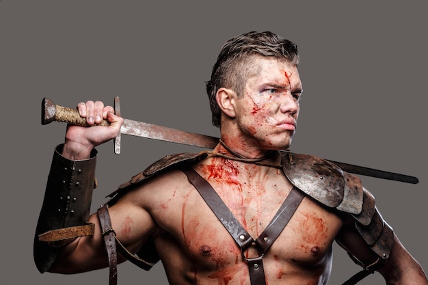 Wounded gladiator with muscular body holding a sword