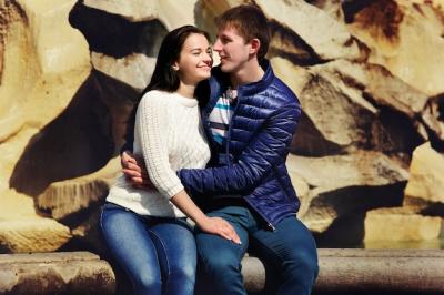 Young couple hugs each other before stone wall