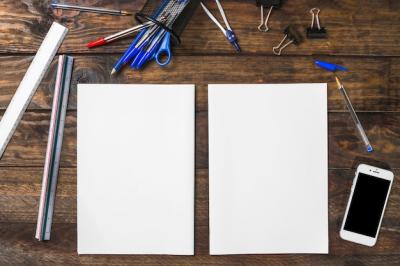 White blank paper surrounded with stationeries and smartphone on wooden table – Free Stock Photo