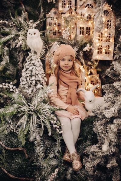 Adorable Brunette Girl in Peach Knitted Hat and Scarf with Christmas Decorations