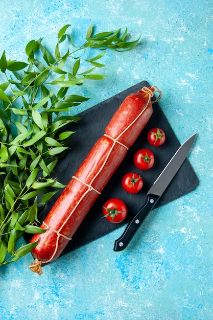 Top view tasty sausage with red tomatoes on a light blue background color food burger meal sandwich meat bread