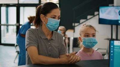 Mother and Child with Face Mask Talking to Receptionist at Hospital Reception Counter During Covid-19 Pandemic