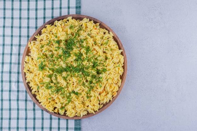 Tray of cooked brown rice topped with dill on marble background