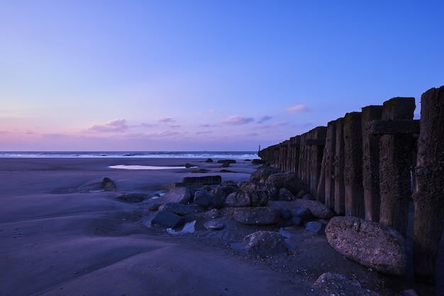 Beautiful Sunset with Purple Clouds Over Fence on Beach