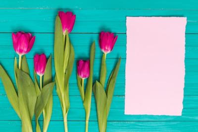 Elevated View of Pink Tulips Flowers with Blank Paper on Green Wooden Background