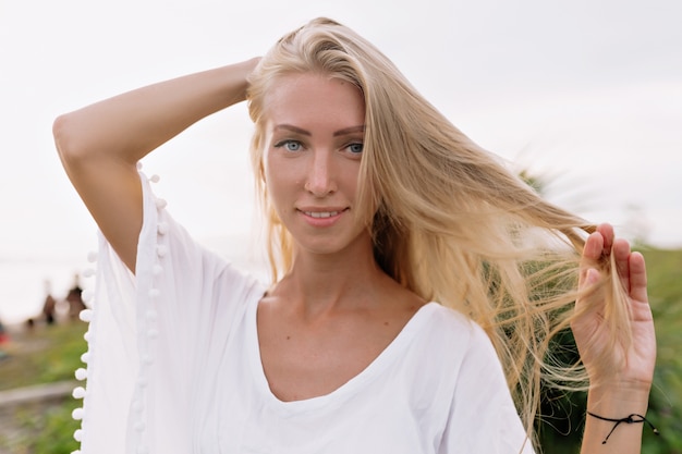 Carefree Smiling Woman in White Blouse Enjoying Leisure Time on Beach