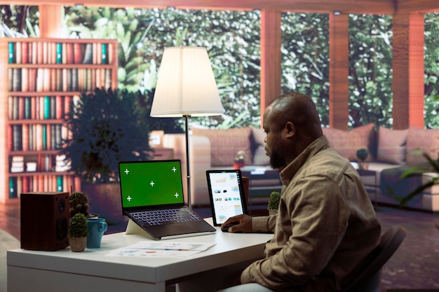 Entrepreneur Examines Financial Statistics Next to a Green Screen at Home Desk