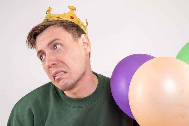 Young male holding colorful balloons on white